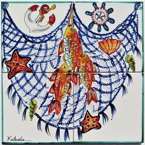 May include: A white ceramic tile with a blue and white fishing net design. The net is filled with orange and yellow fish, a red starfish, and a blue and white ship's wheel. The tile is signed "Kaleidos".