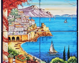 May include: A four-panel ceramic tile mural depicting a colorful Italian coastal scene. The mural features a town built on a cliff overlooking a blue sea with sailboats. The town is surrounded by lush greenery and a red-leafed tree. The bottom panel features the word "Amalfi" in cursive.