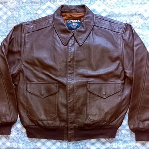 Puede incluir: Chaqueta bomber de cuero marrón con cuello, dos bolsillos delanteros y puños y dobladillo acanalados. La chaqueta tiene una etiqueta US Wings en el cuello. Un estilo clásico, adecuado para diversas ocasiones.