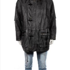 Puede incluir: Una chaqueta de cuero negra con capucha y varios bolsillos. La chaqueta tiene un cierre de botón y una cintura con cordón.