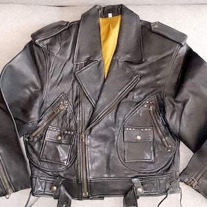 May include: A black leather motorcycle jacket with zippered pockets and a snap closure. The jacket has a yellow lining and a studded design.