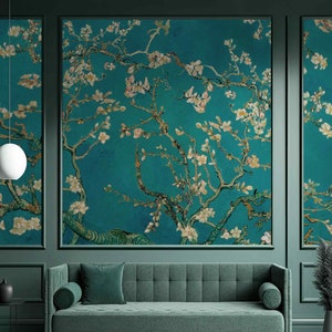 Puede incluir: Una pared verde azulada con tres paneles que presentan una impresión floral de un almendro en flor. Los paneles están enmarcados en negro y la pared está decorada con una lámpara colgante blanca y un sofá verde.
