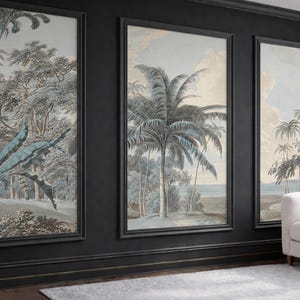 以下が含まれることがあります： 熱帯の風景を描いた3つの額入りウォールアート。ヤシの木、緑豊かな葉、穏やかな空が、青、グレー、ベージュの落ち着いた色合いで描かれています。黒いフレームが作品の優雅さを引き立てています。