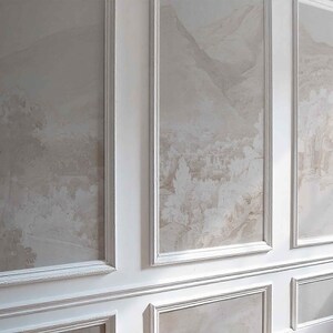 May include: A wall with three framed panels displaying a muted landscape design in beige and brown tones. The panels are set within white moulding, creating a classic, elegant aesthetic. The lower section of the wall also has decorative moulding.