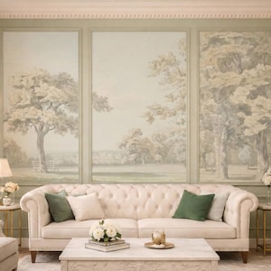 May include: An elegant living room featuring a cream-coloured, tufted sofa with green and cream cushions. A marble coffee table sits in front of the sofa. The wall displays a triptych mural of a landscape scene. Gold side tables with lamps and flowers add to the decor.