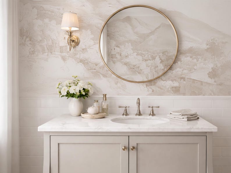 May include: A bathroom vanity with a marble worktop, a round gold mirror, and a floral wallpaper backdrop. The vanity has a white sink, silver tap, and a vase of white flowers. A wall sconce with a lampshade is also visible.
