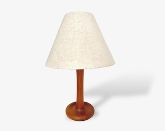 May include: A wooden table lamp with a speckled lampshade. The lamp features a round base and a slender stem, all made of wood. The lampshade is cone-shaped.