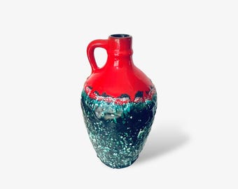 Könnte beinhalten: Eine Keramikvase mit Henkel, mit einem leuchtend roten Oberteil und einem strukturierten, dunkelgrünen Sockel. Die Vase hat eine einzigartige, organische Form und eine glänzende Oberfläche, perfekt für die Inneneinrichtung.