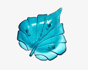 Könnte beinhalten: Eine tealblaue Glasschale in Blattform. Die Schale hat eine strukturierte Oberfläche und eine erhöhte Mitte.