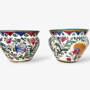 Może przedstawiać: Zestaw trzech ceramicznych kubków z nakrapianą, kremową glazurą. Każdy kubek ma inny, ręcznie malowany kwiatowy wzór w odcieniach niebieskiego, zielonego i żółtego. Kubki mają prosty, nowoczesny kształt.