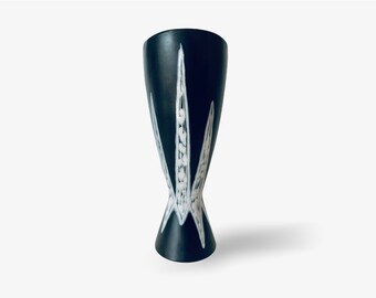 May include: A black ceramic vase with a white geometric design. The vase has a wide mouth and a narrow base.