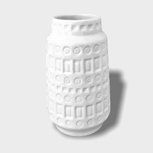 May include: White ceramic vase with a geometric pattern of circles and squares.