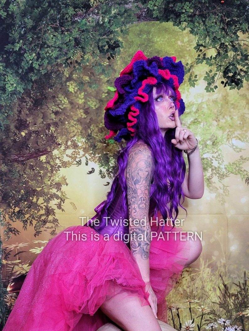 May include: A woman wearing a purple wig and a pink and purple crocheted hat. She is wearing a pink tulle skirt and a purple corset. The text "The Twisted Hatter This is a digital PATTERN" is visible in the image.