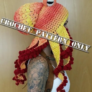 Op de afbeelding: Een gehaakte octopusmuts met een ombre kleurenschema in rood, oranje en geel. De muts heeft een groot hoofd met &eacute;&eacute;n oog en acht tentakels.