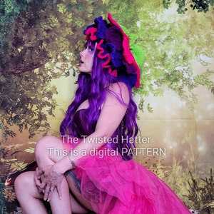 May include: A woman wearing a bright pink and purple crocheted hat with a green brim. The hat is shaped like a mushroom. The woman is wearing a purple corset and a pink tulle skirt. The background is a green and brown leafy pattern.