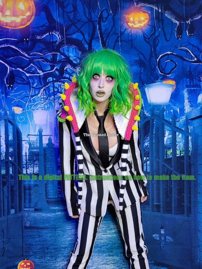 May include: A black and white striped suit with a pink and green crocheted collar and matching scarf. The suit is worn by a person with green hair and white makeup. The background is a blue and black Halloween themed backdrop with jack-o-lanterns.