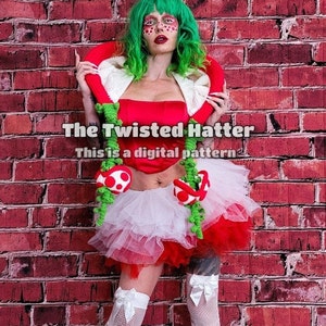 May include: A woman wearing a red and white tutu with green mushroom accents and a red and white top with a green crocheted collar. The text "The Twisted Hatter" and "This is a digital pattern" is visible in the image.