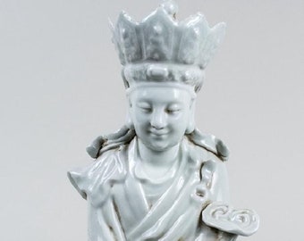 May include: A serene, light-colored ceramic statue of a seated figure, adorned with a crown and flowing robes. The figure is seated on a cloud-like base, with hands gently posed. The statue is approximately 10 inches tall.