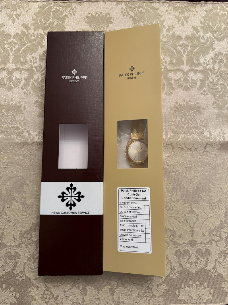 May include: Two brown and gold boxes with the Patek Philippe Geneve logo. The box on the right has a watch inside and a list of items included in the box. The list includes: 1 watch, 1 leather strap with buckle, 1 leather strap with clasp, 1 metal bracelet, 1 complete strap, 2 extra straps, 1 watch tool, 1 watch case back, and a visa operator.