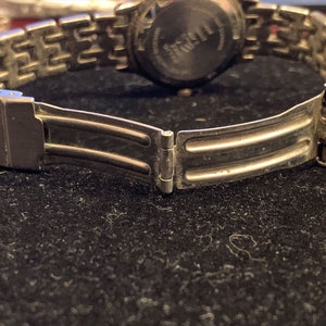 Peut inclure: Un bracelet de montre argent&eacute; avec un fermoir &agrave; double verrouillage. Le bracelet est compos&eacute; de maillons m&eacute;talliques et a une finition polie.