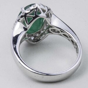 Puede incluir: Un anillo de plata con una gran piedra preciosa verde rodeada de piedras preciosas blancas m&aacute;s peque&ntilde;as.