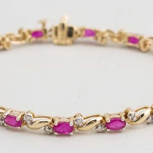 May include: A gold bracelet with a delicate design featuring alternating oval-shaped pink rubies and small round diamonds.