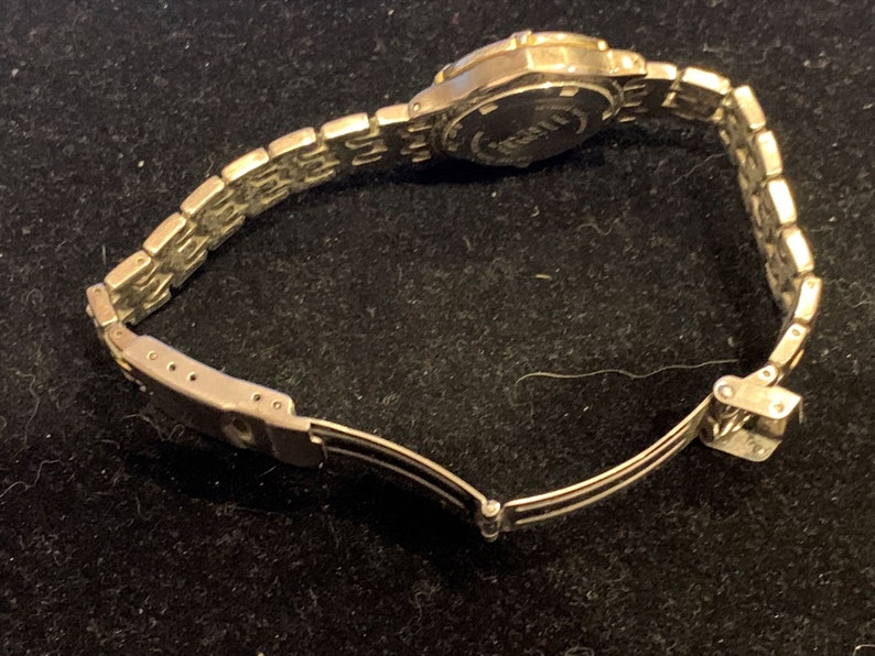 Peut inclure: Une montre argent&eacute;e avec un bracelet en m&eacute;tal argent&eacute;. La montre a un cadran rond et un fermoir argent&eacute;.