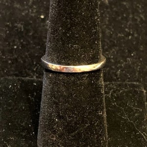 Pu&ograve; includere: Un anello d'argento su un espositore per anelli nero.
