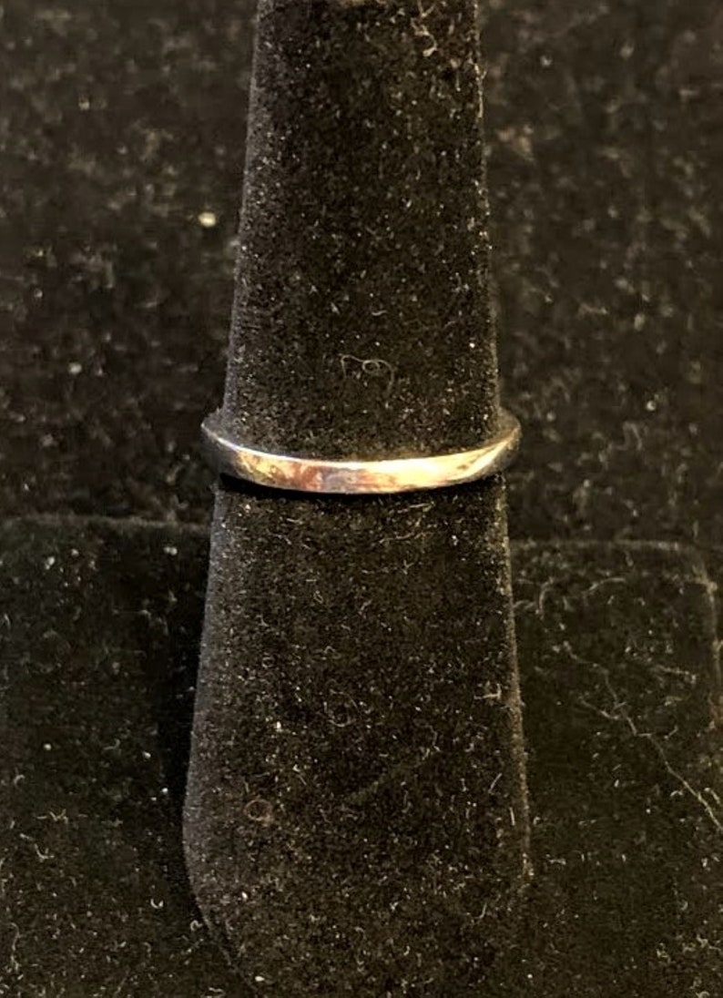 Pu&ograve; includere: Un anello d'argento su un espositore per anelli nero.