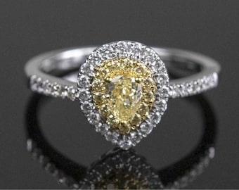 May include: A pear-shaped yellow diamond engagement ring with a halo of smaller diamonds set in white gold.