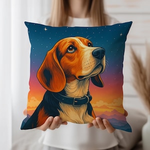 Puede incluir: Un cojín cuadrado con una ilustración de un perro beagle. El perro tiene pelaje marrón y blanco, un collar negro y está ambientado en un cielo nocturno con estrellas y una colorida puesta de sol. El cojín es sostenido por una persona.