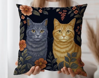 May include: A square throw pillow featuring a dark background with a gray cat and an orange tabby cat sitting side by side. The cats are surrounded by orange flowers, green leaves, and small red berries arranged in a botanical pattern.