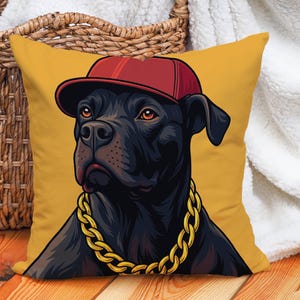 May include: A square decorative pillow with a cartoon illustration of a black dog wearing a red baseball cap and a gold chain necklace. The pillow has a mustard yellow background.