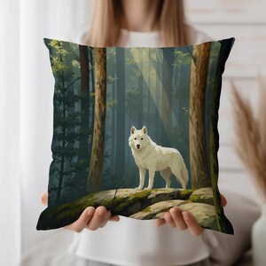 Op de afbeelding: Vierkant decoratief kussen met een witte wolf in een bos. De afbeelding toont een witte wolf op een rots, met hoge bomen en zonlicht dat door de bladeren schijnt. Het kussen heeft een donkere rand.