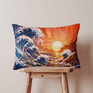 May include: Rectangular pillow featuring a stylized ocean wave design with a sunset backdrop. The pillow showcases a large, curling wave in shades of blue and white, set against a vibrant orange and yellow sky with a large sun. The pillow is placed on a wooden stool.