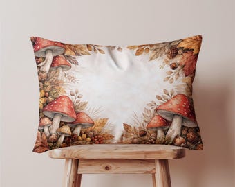 May include: Rectangular cushion with a watercolour design of red-capped mushrooms with white spots, surrounded by autumn leaves, pine cones, and berries. The cushion has a cream background, creating a cosy, seasonal aesthetic.