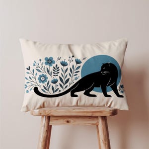 Peut inclure: Coussin rectangulaire crème avec une silhouette de panthère noire sur un cercle bleu. Motif floral bleu et vert foncé à gauche. Coussin décoratif pour la décoration intérieure.