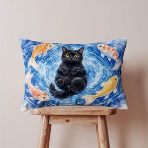May include: A decorative pillow featuring a black cat surrounded by koi fish in a blue swirling water design. The cat has yellow eyes and is lying on its back. The koi fish are orange and white.