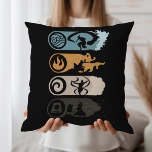 May include: Black cushion featuring four elemental symbols: water, fire, air, and earth. Each symbol is accompanied by a silhouette of a person in action, set against a coloured background. The cushion is held by a person.