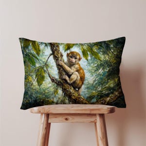 Peut inclure: Coussin rectangulaire décoratif avec une peinture détaillée d'un singe perché sur une branche d'arbre. Le singe a une fourrure brune et est entouré d'un feuillage vert luxuriant. Le coussin est posé sur un tabouret en bois.