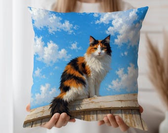 May include: Square throw pillow featuring a fluffy calico cat with orange, black, and white fur, set against a bright blue sky with fluffy white clouds. The cat is perched on a wooden fence. Decorative home accent.