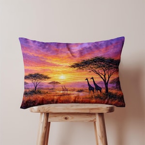 Könnte beinhalten: Rechteckiges Zierkissen mit einer afrikanischen Sonnenuntergangsszene. Das Bild zeigt Giraffen, Bäume und einen farbenfrohen Himmel in Orange-, Lila- und Gelbtönen. Das Kissen liegt auf einem Holzschemel.