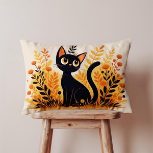 Peut inclure: Un coussin rectangulaire avec une illustration de chat noir aux grands yeux jaunes, assis au milieu d'un feuillage orange et jaune. Le chat a une queue courbée et des oreilles pointues. Le coussin est sur un tabouret en bois.