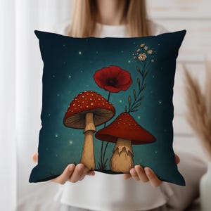 May include: Square decorative pillow with a whimsical illustration of red mushrooms with white spots and a red poppy against a dark teal background. The pillow has a soft, inviting appearance, perfect for adding a touch of nature-inspired art to any space.