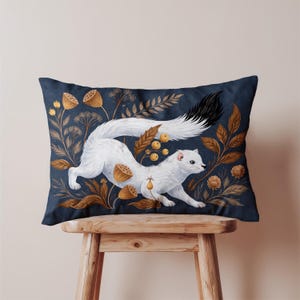 Peut inclure: Un coussin rectangulaire avec un motif d'hermine blanche à queue noire sur fond bleu foncé. Le design comprend du feuillage et des capsules de graines brun doré, créant un thème inspiré de la nature.