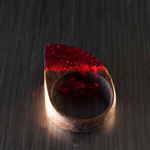 以下が含まれることがあります： 木製のバンドが付いた赤いレジンリング。レジンはキラキラした仕上げです。