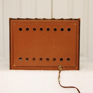 May include: The back of a brown wooden radio with a cord attached. The radio has a series of small holes in the back.