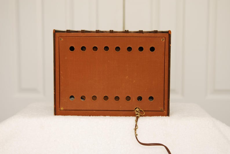 May include: The back of a brown wooden radio with a cord attached. The radio has a series of small holes in the back.