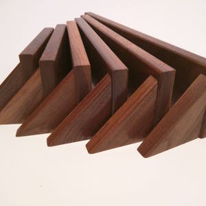 May include: A set of eight wooden triangular shelves in various shades of brown. The shelves are arranged in a fan shape, with the largest shelf at the top and the smallest shelf at the bottom.