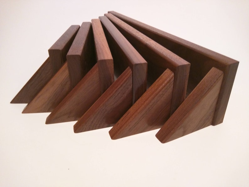 May include: A set of eight wooden triangular shelves in various shades of brown. The shelves are arranged in a fan shape, with the largest shelf at the top and the smallest shelf at the bottom.
